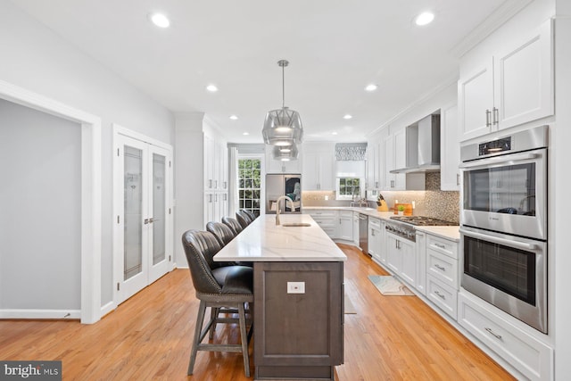 20736 Ashburn Station Pl, Ashburn, VA 20147 - kitchen featuring stainless steel appliances, wall chimney exhaust hood, decorative backsplash, an island with sink, and white cabinets