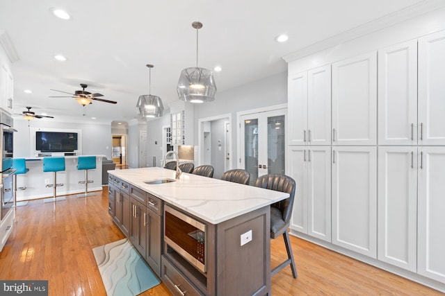20736 Ashburn Station Pl, Ashburn, VA 20147 - kitchen featuring appliances with stainless steel finishes, a kitchen bar, white cabinetry, light wood-style flooring, and recessed lighting