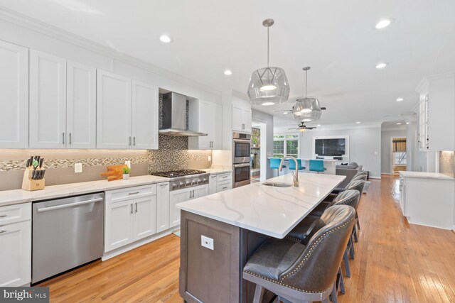 20736 Ashburn Station Pl, Ashburn, VA 20147 - kitchen featuring stainless steel appliances, wall chimney range hood, open floor plan, crown molding, and white cabinetry