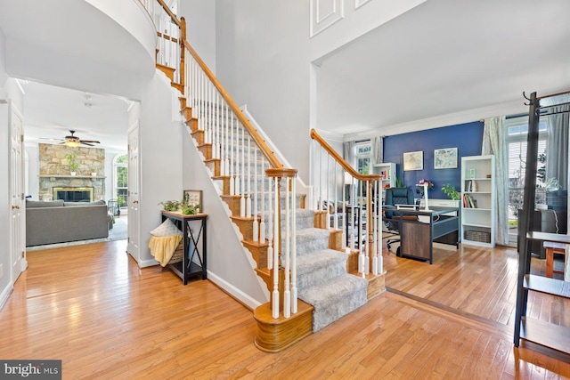20736 Ashburn Station Pl, Ashburn, VA 20147 - entrance foyer with hardwood / wood-style floors, stairway, ceiling fan, a fireplace, and a towering ceiling