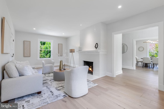 6818 Connecticut Ave, Chevy Chase, MD 20815 - living area featuring wood finished floors, a warm lit fireplace, recessed lighting, and a chandelier