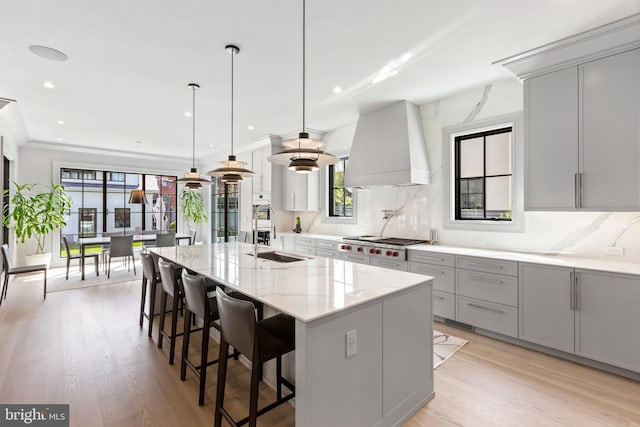 3119 38th St NW, Washington, DC 20016 - kitchen with custom exhaust hood, gray cabinetry, stainless steel gas cooktop, light wood-type flooring, and recessed lighting