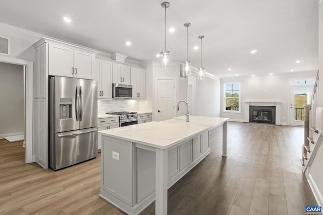 103 Laconia Ln, Charlottesville, VA 22911 - kitchen featuring appliances with stainless steel finishes, backsplash, light wood-style floors, an island with sink, and light stone counters