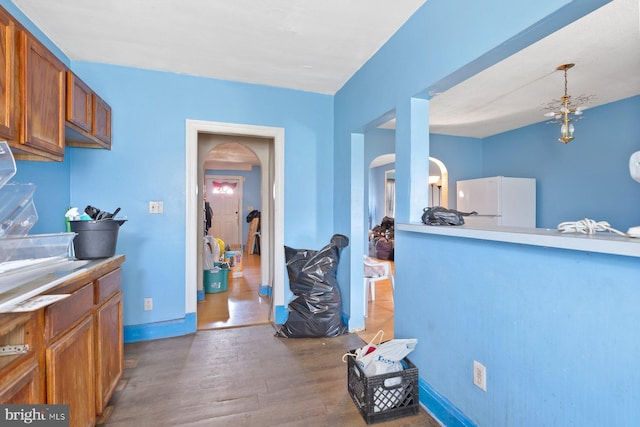 11 Rosedale St, Baltimore, MD 21229 - kitchen with brown cabinetry, arched walkways, wood finished floors, freestanding refrigerator, and decorative light fixtures