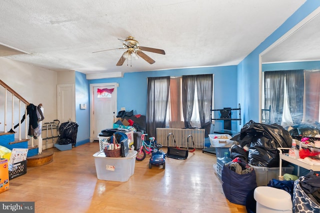 11 Rosedale St, Baltimore, MD 21229 - living area featuring radiator, ceiling fan, hardwood / wood-style floors, stairs, and a textured ceiling