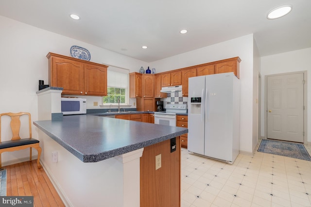 3 Baird Ct, Carlisle, PA 17013 - kitchen featuring white appliances, a peninsula, under cabinet range hood, dark countertops, and brown cabinetry
