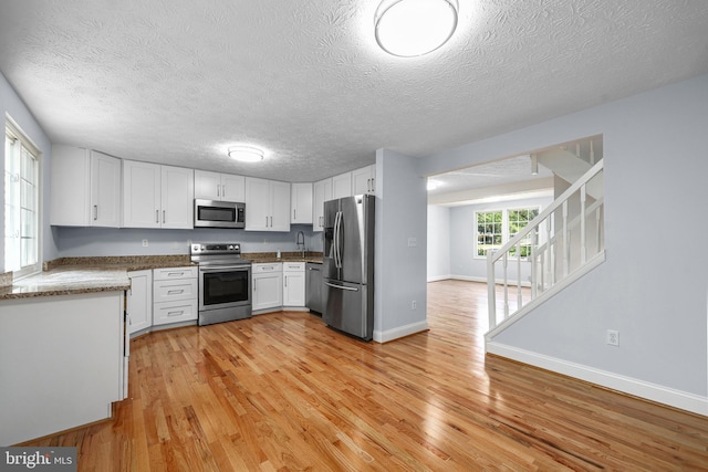 1632 Barnstead Dr, Reston, VA 20194 - kitchen with stainless steel appliances, light wood finished floors, white cabinetry, a textured ceiling, and dark stone countertops