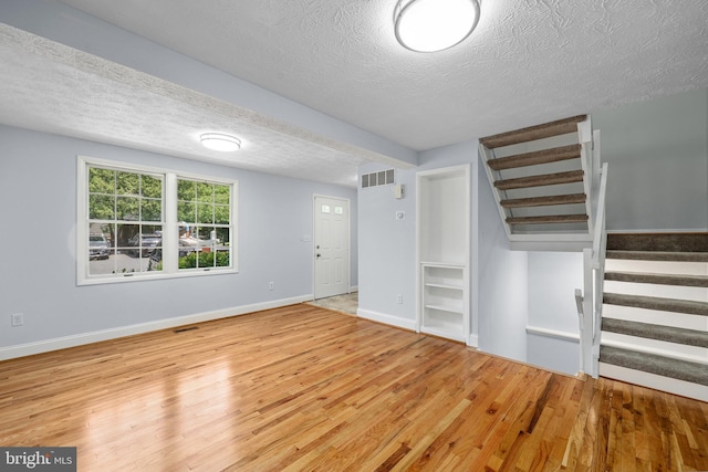 1632 Barnstead Dr, Reston, VA 20194 - unfurnished living room with a textured ceiling, wood finished floors, and stairs