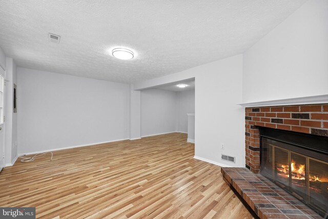 1632 Barnstead Dr, Reston, VA 20194 - unfurnished living room featuring light wood-style floors, a brick fireplace, and a textured ceiling
