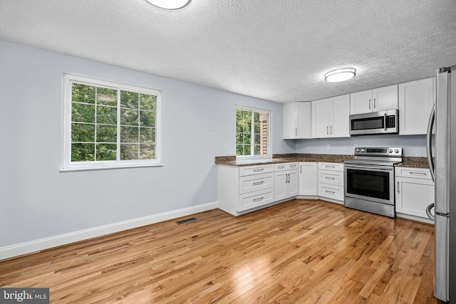 1632 Barnstead Dr, Reston, VA 20194 - kitchen featuring appliances with stainless steel finishes, light wood-type flooring, white cabinetry, and a textured ceiling