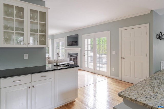 325 Heron Ln, Charlottesville, VA 22903 - kitchen featuring a fireplace, ornamental molding, light wood-type flooring, glass insert cabinets, and white cabinets