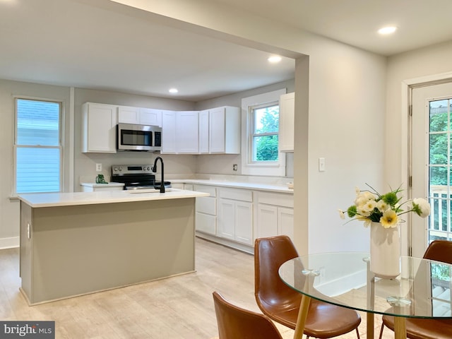 840 Columbia Ave, Cumberland, MD 21502 - kitchen with stainless steel appliances, light countertops, a center island with sink, white cabinets, and light wood-style floors