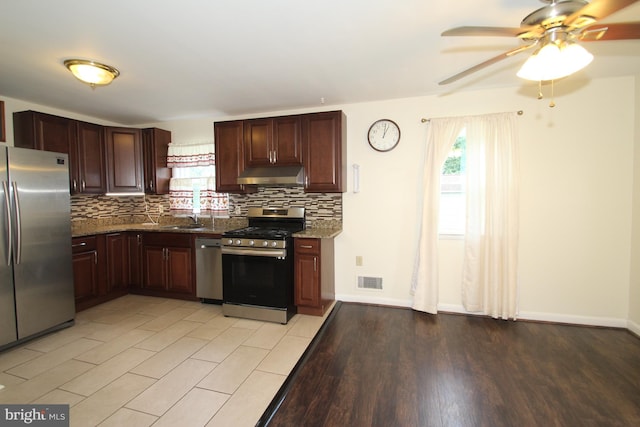 804 N Augustine St, Wilmington, DE 19804 - kitchen featuring appliances with stainless steel finishes, under cabinet range hood, decorative backsplash, ceiling fan, and dark stone countertops