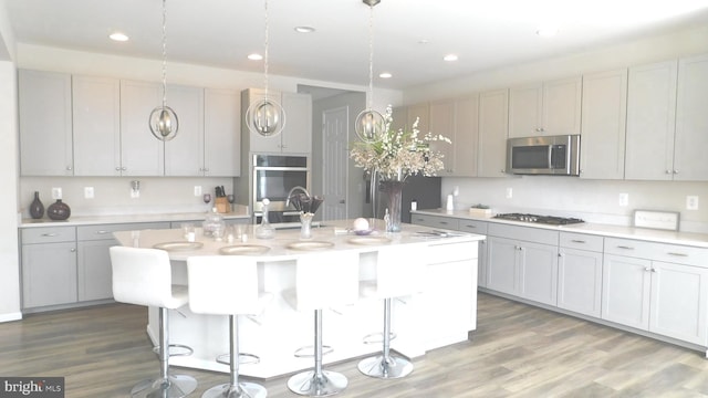 12507 Olivine Ct, Hagerstown, MD 21740 - kitchen featuring stainless steel appliances, light countertops, an island with sink, wood finished floors, and recessed lighting