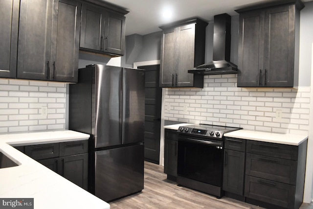 607 N Broom St, Wilmington, DE 19805 - kitchen with stainless steel appliances, wall chimney range hood, decorative backsplash, light countertops, and light wood-style flooring