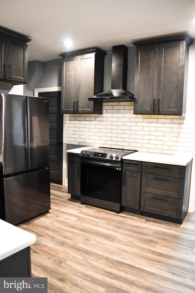 607 N Broom St, Wilmington, DE 19805 - kitchen featuring freestanding refrigerator, stainless steel electric stove, wall chimney exhaust hood, light countertops, and light wood-type flooring