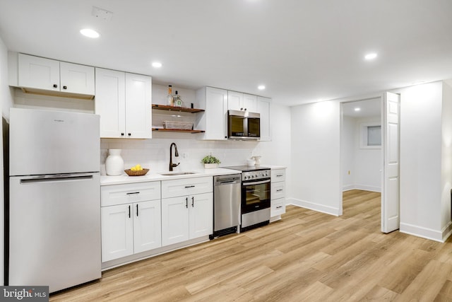 3105 17th St NW, Washington, DC 20010 - kitchen with stainless steel appliances, open shelves, light wood finished floors, white cabinets, and decorative backsplash