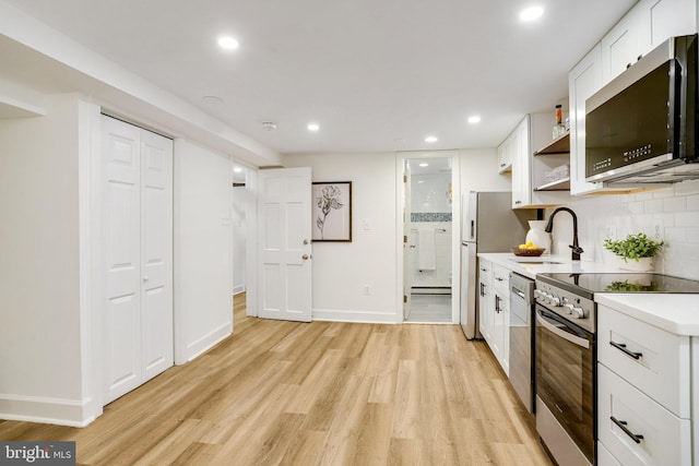 3105 17th St NW, Washington, DC 20010 - kitchen with appliances with stainless steel finishes, light wood-type flooring, light countertops, white cabinets, and recessed lighting