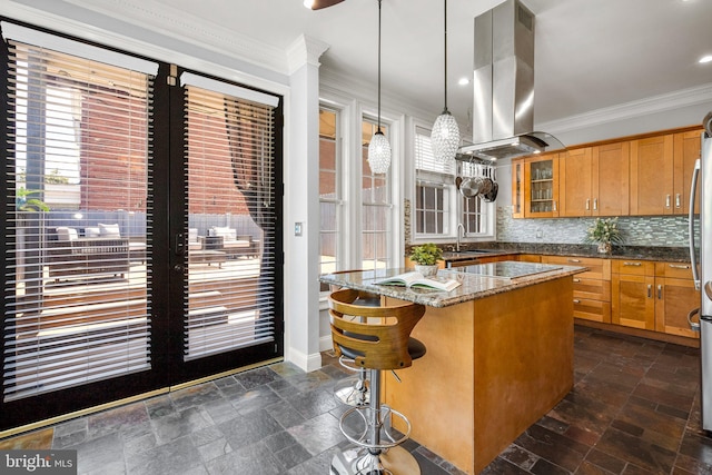 1125 K St NE, Washington, DC 20002 - kitchen featuring island exhaust hood, stone tile floors, glass insert cabinets, ornamental molding, and brown cabinetry