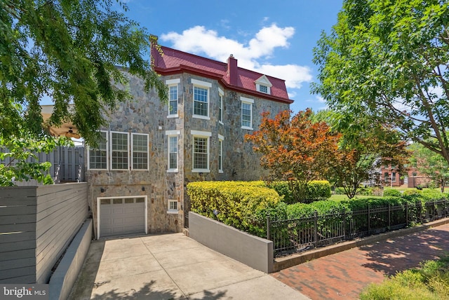 1125 K St NE, Washington, DC 20002 - view of front of house featuring stone siding, a chimney, concrete driveway, a garage, and a high end roof