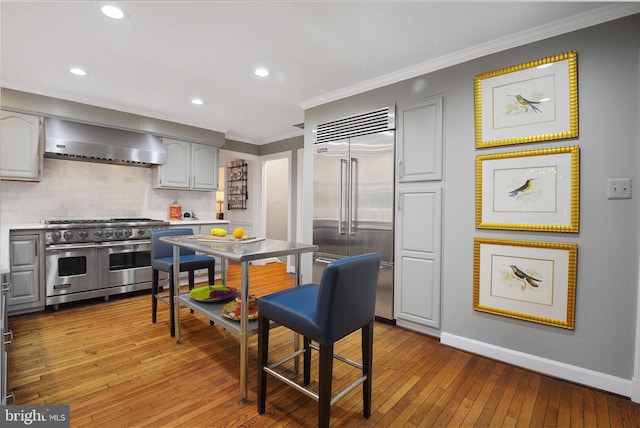 15508 Summer Grove Ct, Gaithersburg, MD 20878 - kitchen with premium appliances, wall chimney range hood, tasteful backsplash, crown molding, and wood-type flooring