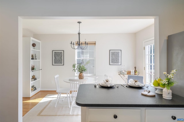 324 NW 8th St, Charlottesville, VA 22903 - kitchen featuring dark countertops, light wood-type flooring, white cabinetry, and a chandelier