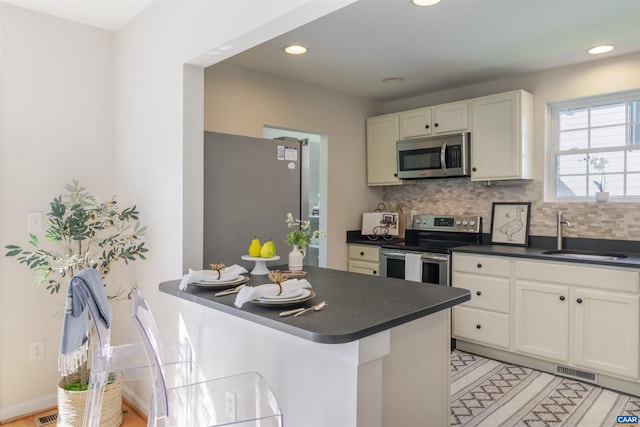 324 NW 8th St, Charlottesville, VA 22903 - kitchen with stainless steel appliances, dark countertops, decorative backsplash, white cabinetry, and recessed lighting