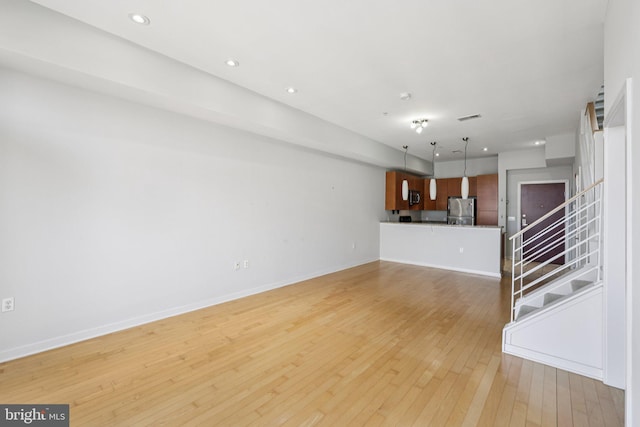 1209 N Charles St Unit 409, Baltimore, MD 21201 - unfurnished living room with light wood finished floors, stairs, and recessed lighting