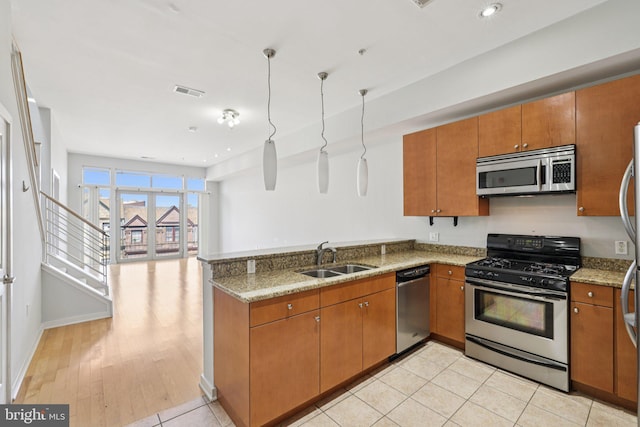 1209 N Charles St Unit 409, Baltimore, MD 21201 - kitchen featuring appliances with stainless steel finishes, brown cabinets, a peninsula, light stone counters, and recessed lighting