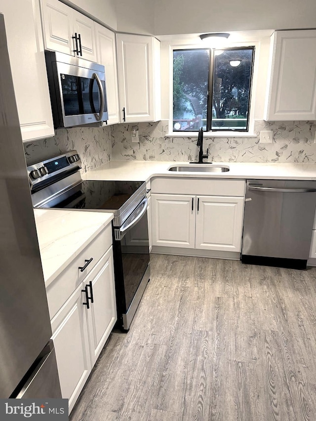 54 Liborio Ln, New Castle, DE 19720 - kitchen with appliances with stainless steel finishes, light wood finished floors, white cabinetry, and decorative backsplash