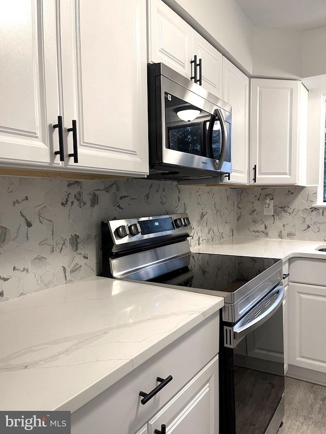 54 Liborio Ln, New Castle, DE 19720 - kitchen featuring stainless steel appliances, white cabinetry, tasteful backsplash, light wood-type flooring, and light stone counters
