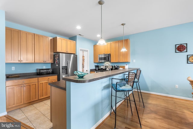 37166 Gull Watch Way Unit 1315, Selbyville, DE 19975 - kitchen with appliances with stainless steel finishes, dark countertops, a kitchen breakfast bar, a peninsula, and hanging light fixtures