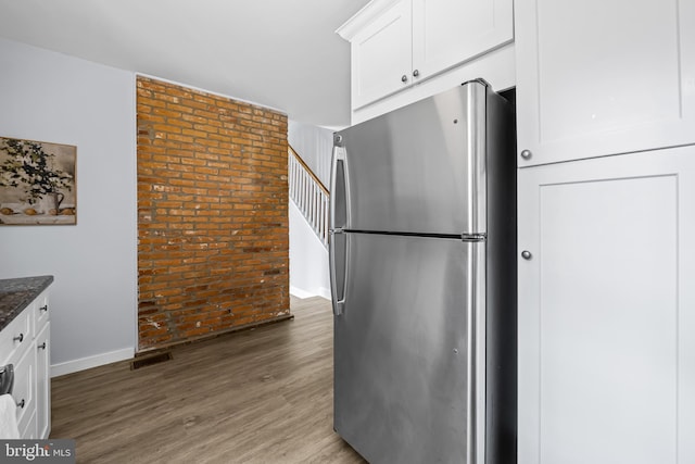 239 W Lafayette Ave, Baltimore, MD 21217 - kitchen featuring freestanding refrigerator, brick wall, dark stone countertops, white cabinets, and light wood-type flooring