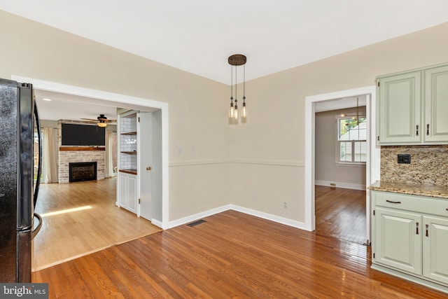 301 Fleming Ave, Frederick, MD 21701 - unfurnished dining area with a ceiling fan, light wood-style flooring, and a brick fireplace