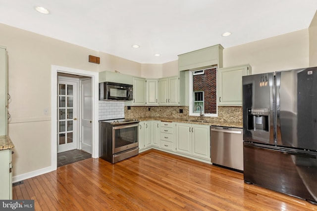 301 Fleming Ave, Frederick, MD 21701 - kitchen with stainless steel appliances, light stone countertops, light wood-style flooring, decorative backsplash, and recessed lighting