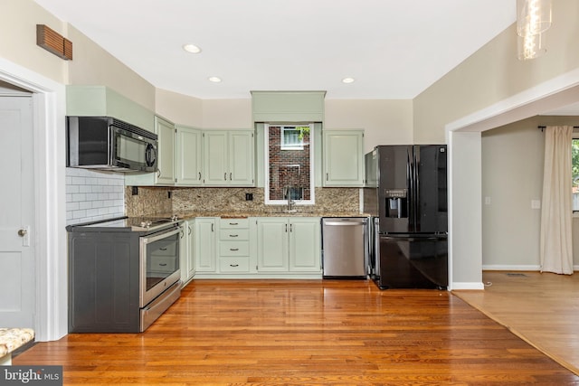 301 Fleming Ave, Frederick, MD 21701 - kitchen featuring black appliances, green cabinetry, decorative backsplash, light wood-style floors, and recessed lighting
