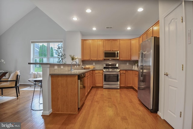 44357 Oakmont Manor Sq, Ashburn, VA 20147 - kitchen featuring stainless steel appliances, light wood finished floors, a peninsula, decorative backsplash, and a kitchen breakfast bar