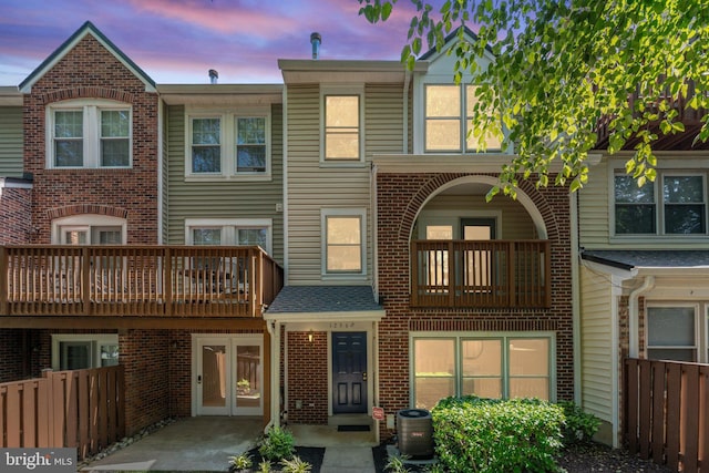 12560 Kempston Ln, Woodbridge, VA 22192 - back of house at dusk featuring a balcony, french doors, and brick siding