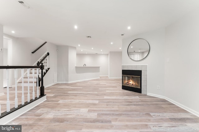 12560 Kempston Ln, Woodbridge, VA 22192 - unfurnished living room featuring light wood-style floors, stairs, recessed lighting, and a tile fireplace