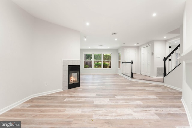 12560 Kempston Ln, Woodbridge, VA 22192 - unfurnished living room with recessed lighting, a tiled fireplace, light wood-type flooring, and stairway