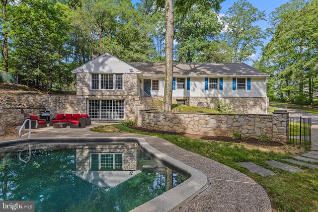 13 Weirwood Rd, Wayne, PA 19087 - rear view of house featuring stone siding, an outdoor living space, a patio, an outdoor pool, and a chimney