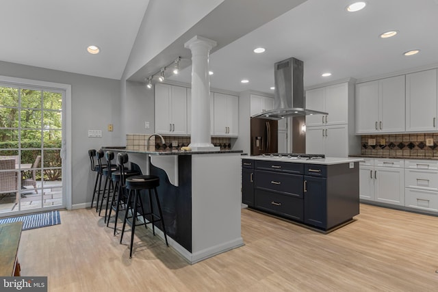 13 Weirwood Rd, Wayne, PA 19087 - kitchen featuring island range hood, decorative columns, light wood finished floors, backsplash, and recessed lighting