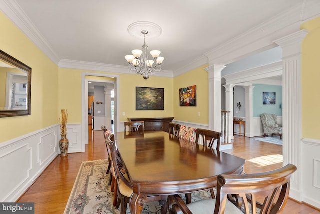 14512 Penderlea Ct, Gainesville, VA 20155 - dining area featuring light wood-type flooring, ornate columns, ornamental molding, a chandelier, and wainscoting