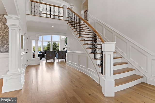 2740 Allen Glen Dr, Mechanicsburg, PA 17055 - staircase with a decorative wall, ornate columns, hardwood / wood-style flooring, a high ceiling, and wainscoting
