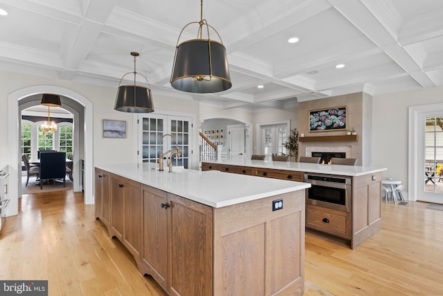 2740 Allen Glen Dr, Mechanicsburg, PA 17055 - kitchen with a large island, arched walkways, coffered ceiling, light wood-style floors, and a warm lit fireplace