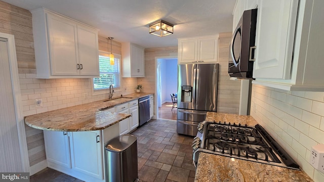 93 W Center St, Glen Rock, PA 17327 - kitchen with appliances with stainless steel finishes, white cabinets, a peninsula, light stone counters, and decorative backsplash