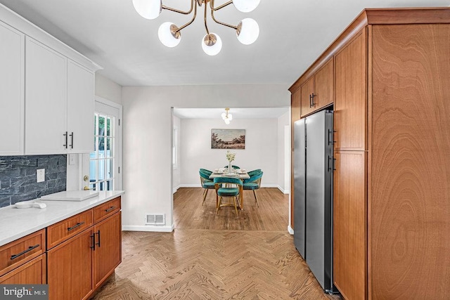 1528 Stuyvesant Ave, Trenton, NJ 08618 - kitchen featuring freestanding refrigerator, a chandelier, decorative backsplash, light countertops, and brown cabinetry