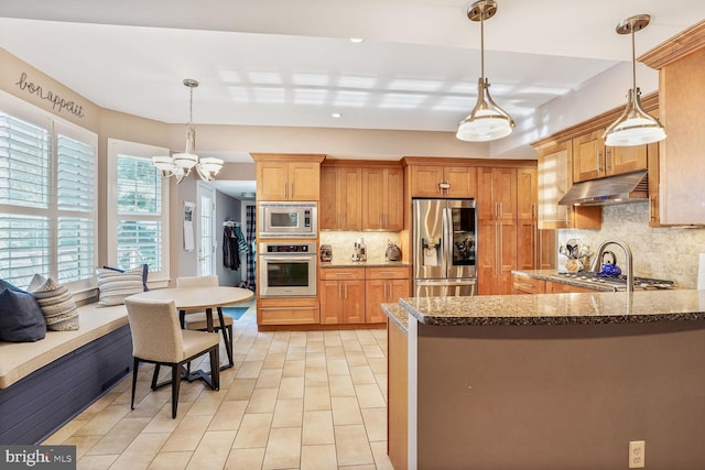 47643 Rhyolite Pl, Sterling, VA 20165 - kitchen featuring appliances with stainless steel finishes, under cabinet range hood, decorative backsplash, pendant lighting, and dark stone counters