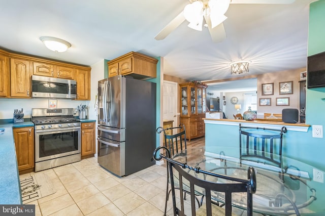 8905 Dewees St, Philadelphia, PA 19152 - kitchen featuring appliances with stainless steel finishes, dark countertops, brown cabinets, and light tile patterned floors