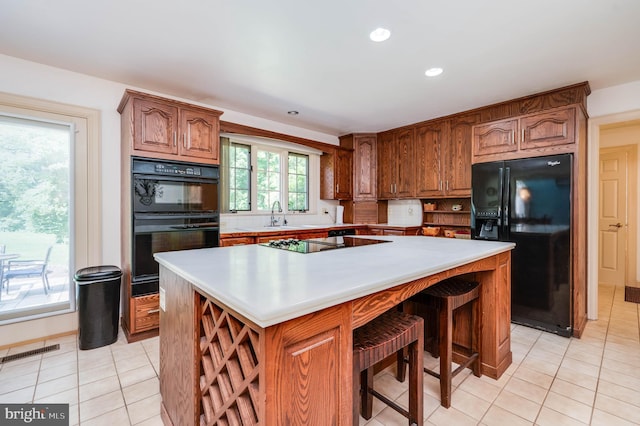 14 Quail Ridge Dr, Reading, PA 19607 - kitchen featuring black appliances, light tile patterned floors, a center island, brown cabinets, and recessed lighting